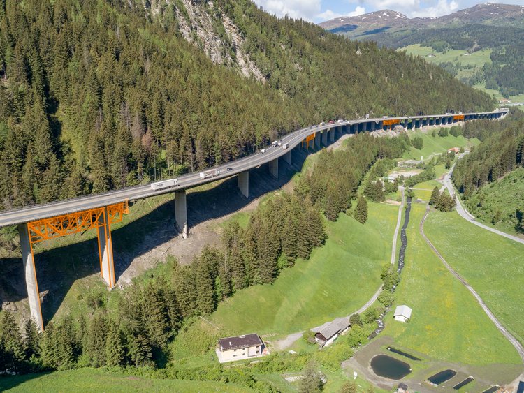 Mountain landscape with a long bridge built on a steep slope showing a support structure drawn in at four points on the underside.