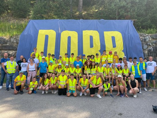 Large group of children in front of a large construction fence banner with the PORR logo