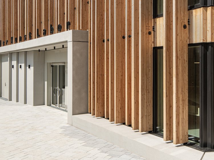 Vorderansicht des Haupteingangsbereichs eines Gebäudes mit Holzfassade und klar definiertem Eingangsbereich.