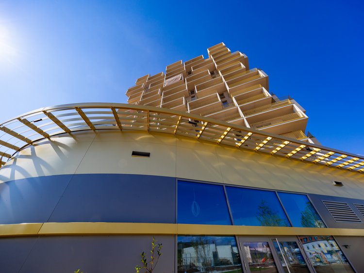 Hochhaus mit geschwungener goldener Stahlabgrenzung des Erdgeschosses